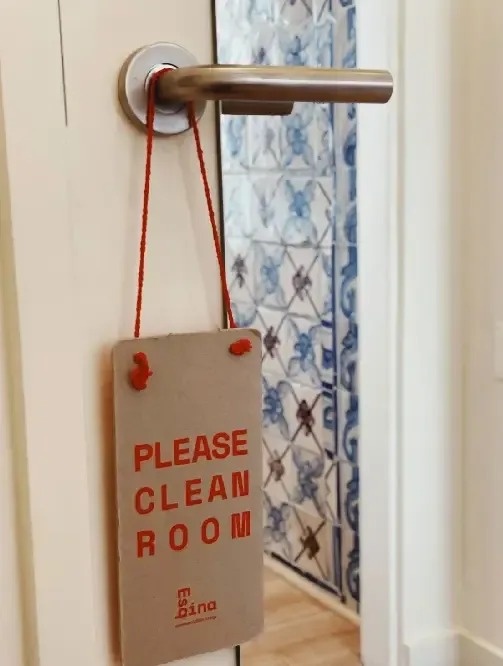un cartel colgando de una manija de puerta que dice " por favor limpie la habitación " .