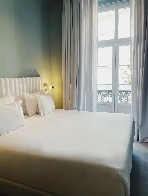 una habitación con una cama y una ventana con cortinas blancas