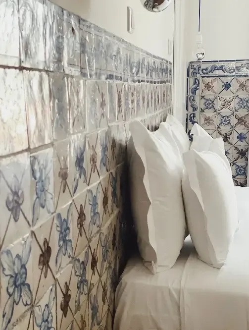 a bed with a blue and white tiled wall behind it