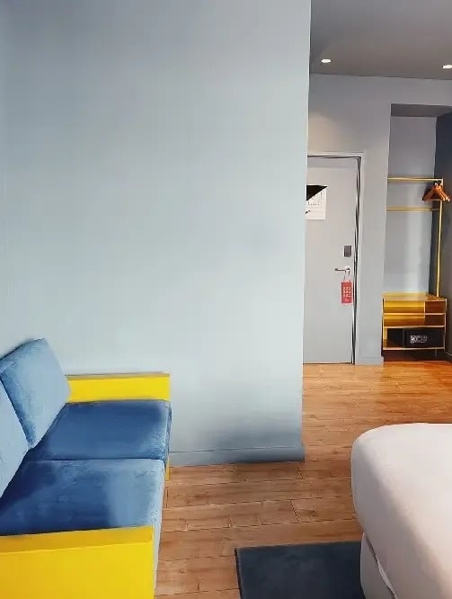 a hotel room with a blue couch and yellow arm rests