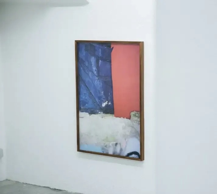 a large painting is hanging on a white wall in a room .