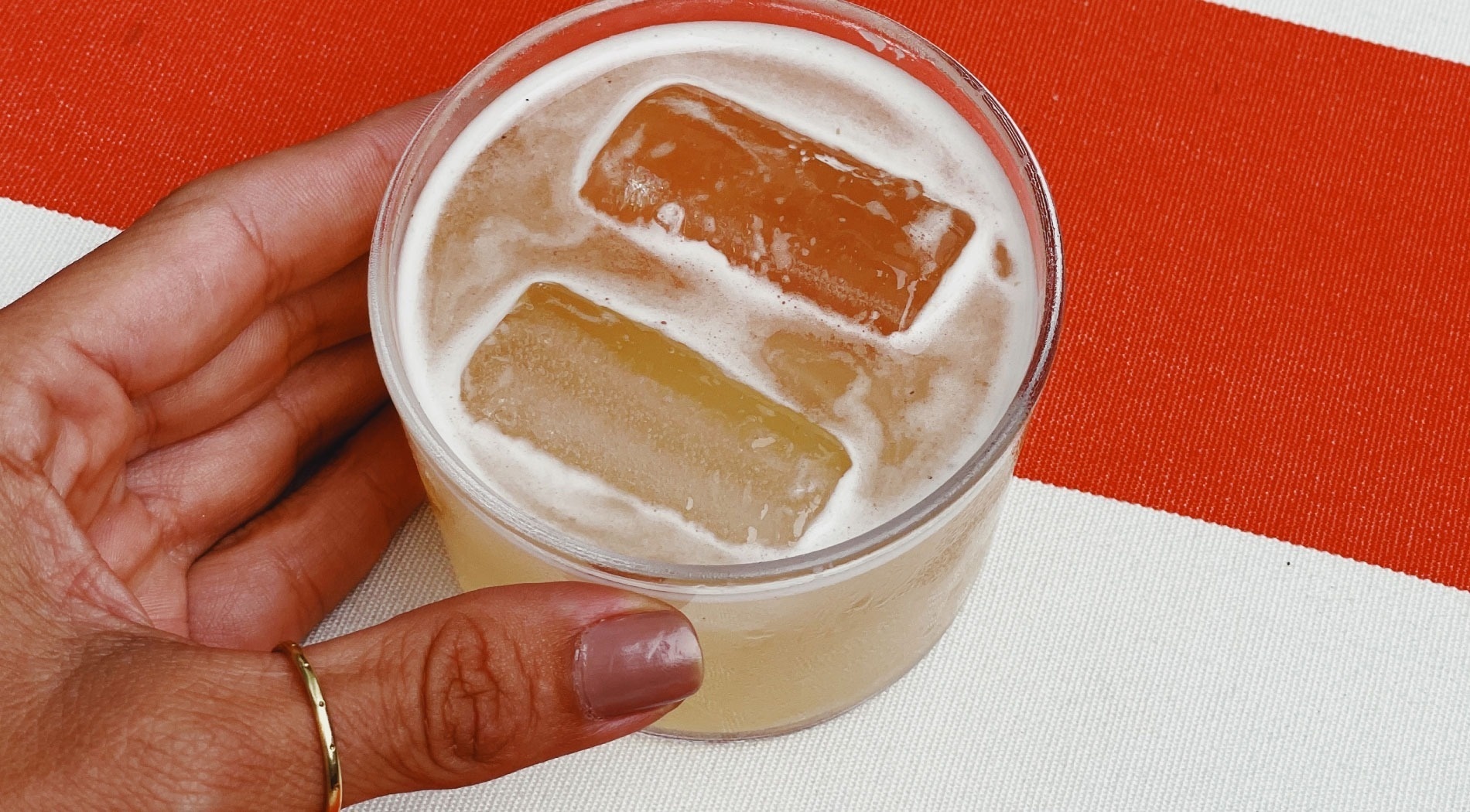 a hand is holding a glass with ice cubes in it