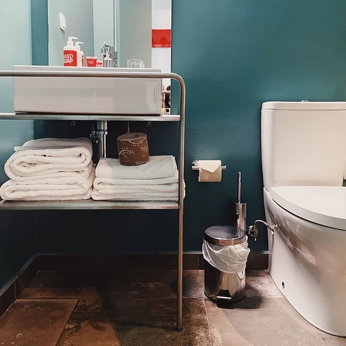 a bathroom with a toilet a sink and a trash can