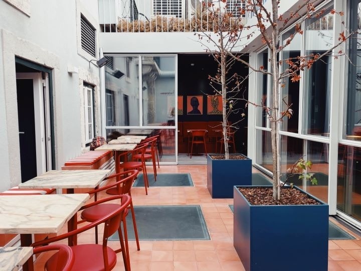 um restaurante com mesas e cadeiras vermelhas e vasos de plantas