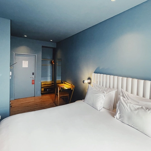 a hotel room with a white bed and blue walls