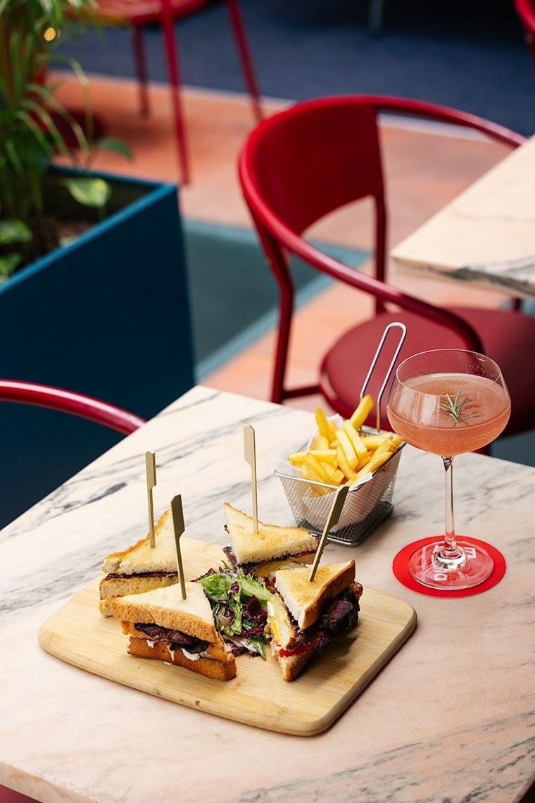 a sandwich on a cutting board next to a basket of french fries