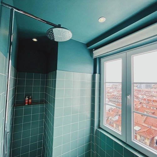 a bathroom with green tiles and a window with a view of a city