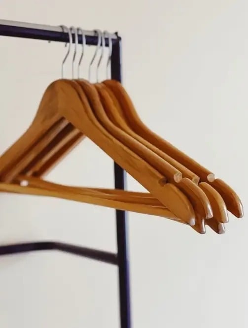 un montón de perchas de madera colgadas en un rack de ropa .