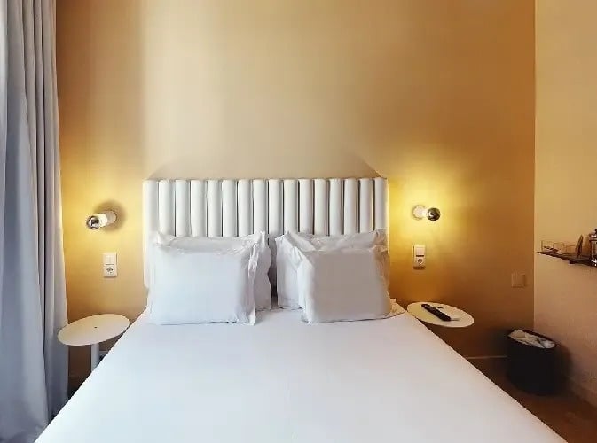 a bed with white sheets and pillows in a hotel room
