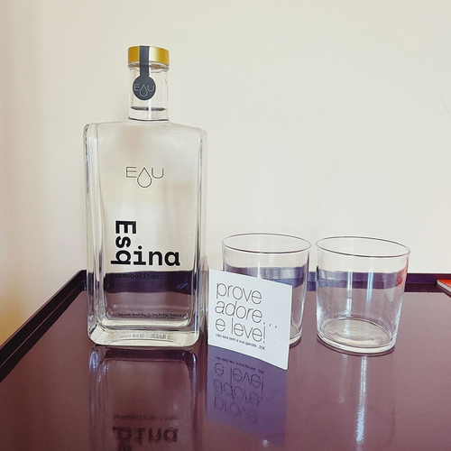 a bottle of eau espina sits on a table next to two glasses