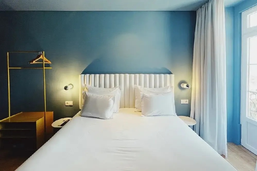 una habitación con una cama blanca y una pared azul
