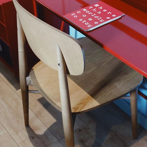 a wooden chair sits in front of a red desk with a book on it that says where the world comes to stay