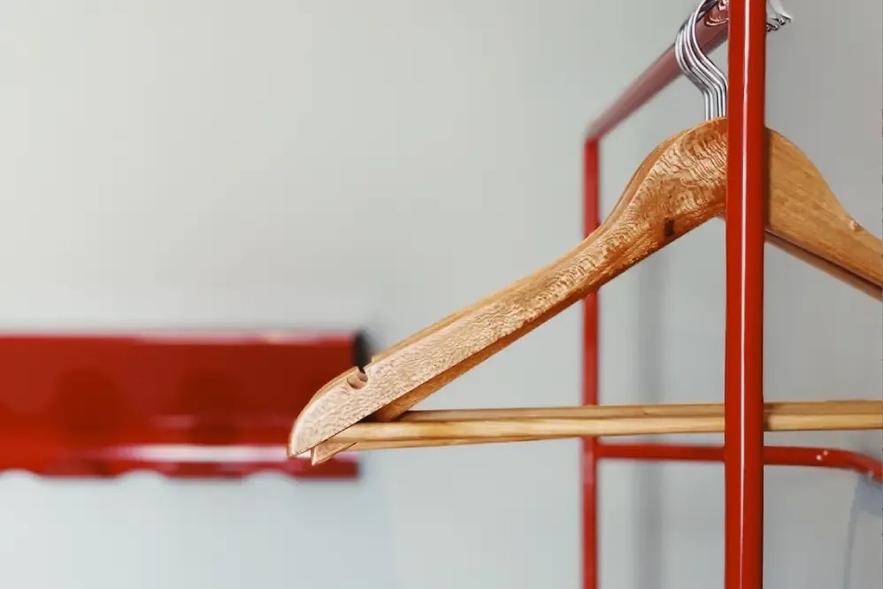 a row of wooden hangers hanging on a red rack