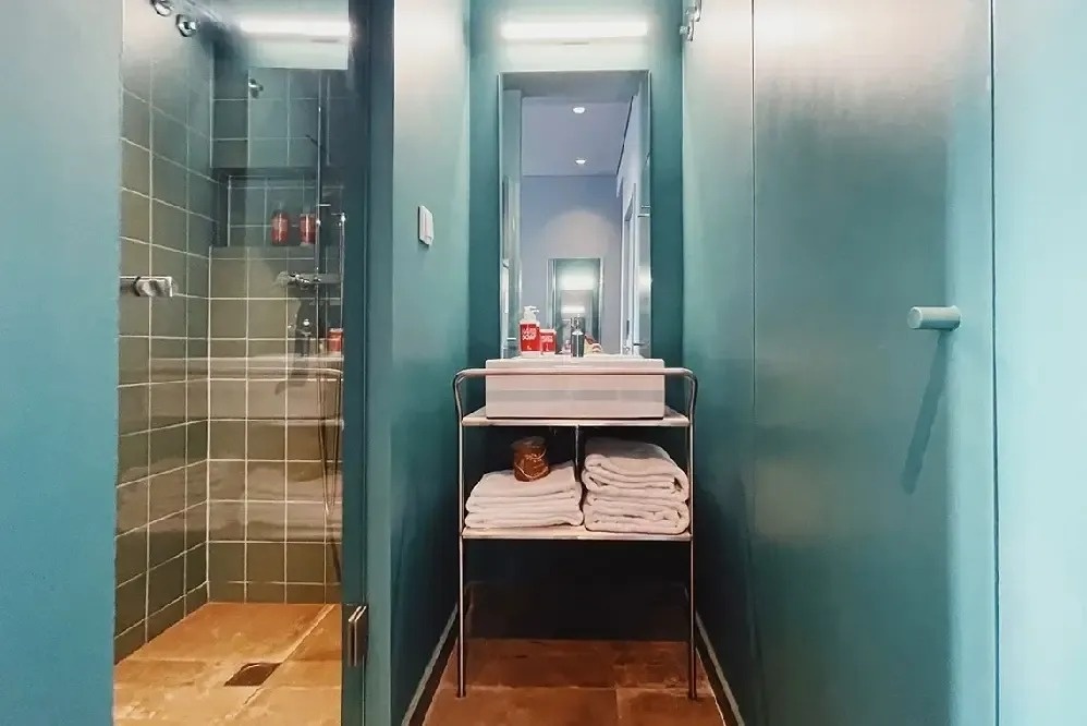 un baño azul con un lavabo y una ducha