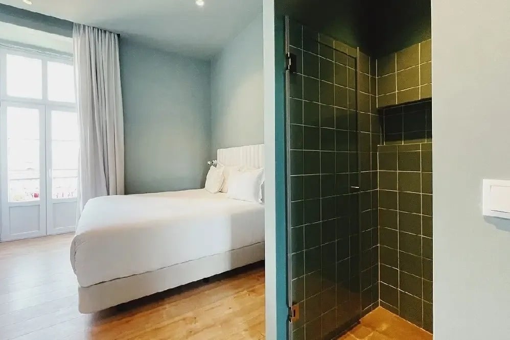 una habitación con una cama y un baño con azulejos verdes