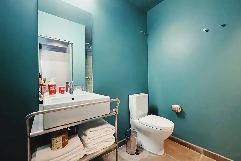 un baño con paredes verdes y un inodoro y un lavabo