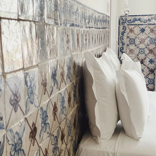 a bed with a blue and white tiled wall behind it
