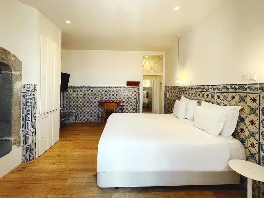 una habitación con una cama blanca y azulejos azules y blancos