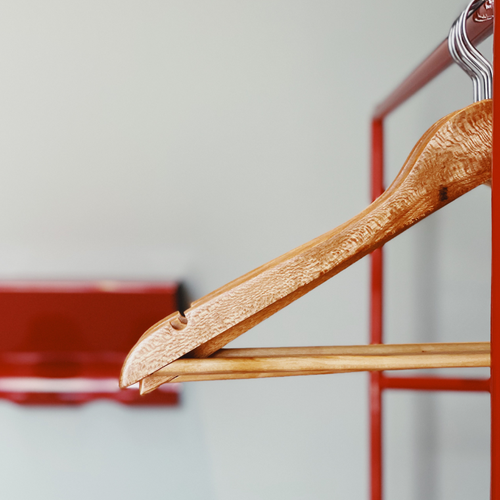 a wooden hanger is hanging on a red rack