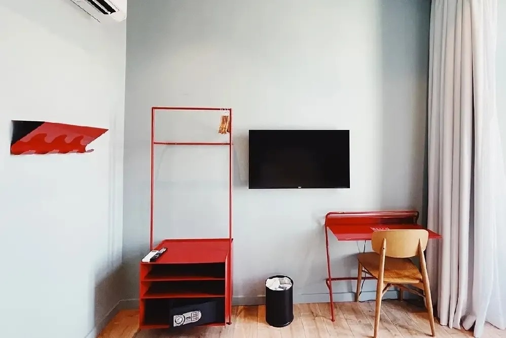 una habitación con un escritorio rojo y una televisión de pantalla plana