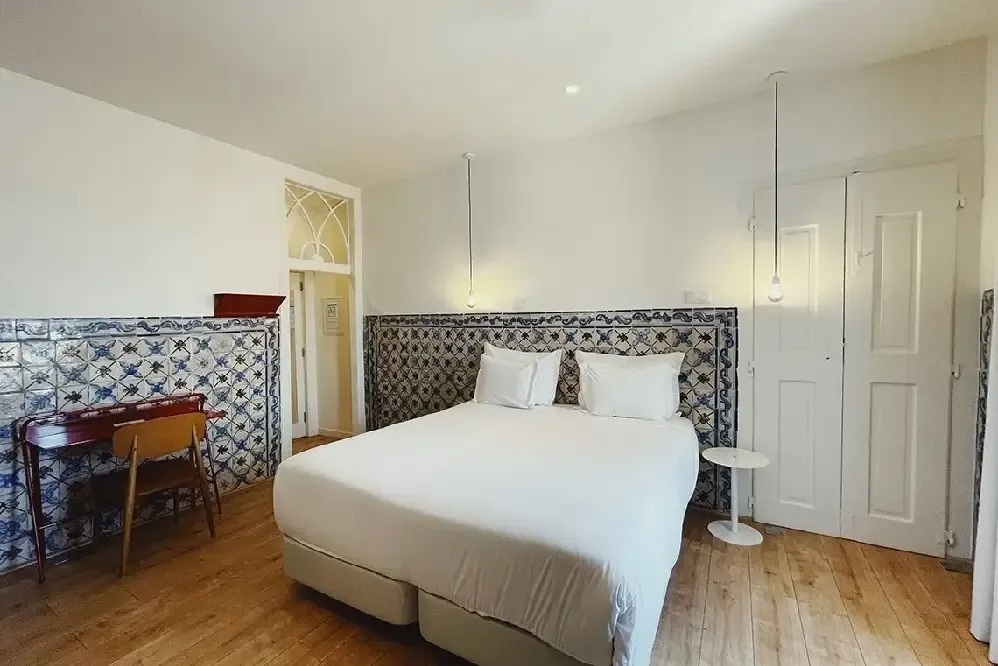 una habitación con una cama blanca y azulejos en las paredes