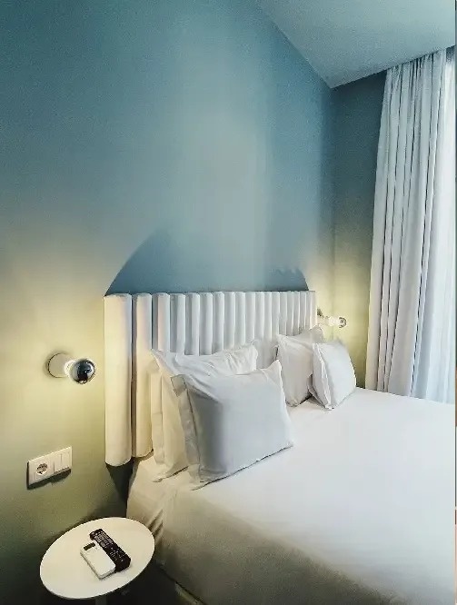 una habitación de hotel con una cama blanca y una pared azul