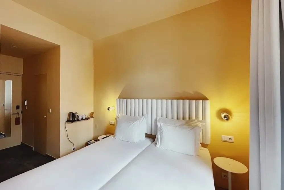 a hotel room with two beds and a yellow wall