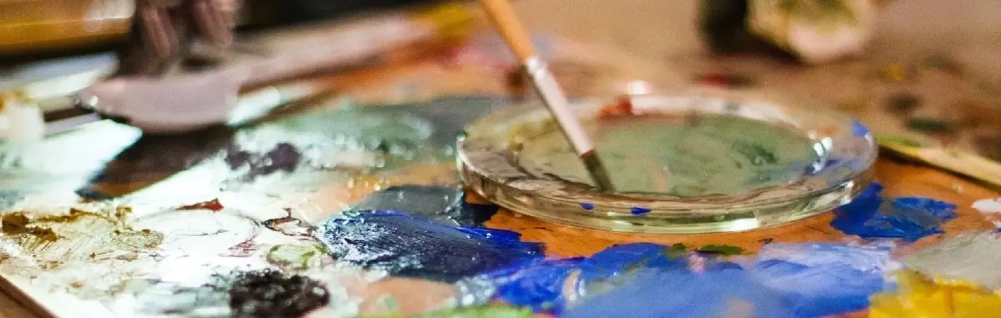 a palette with a brush and a bowl of paint on it .