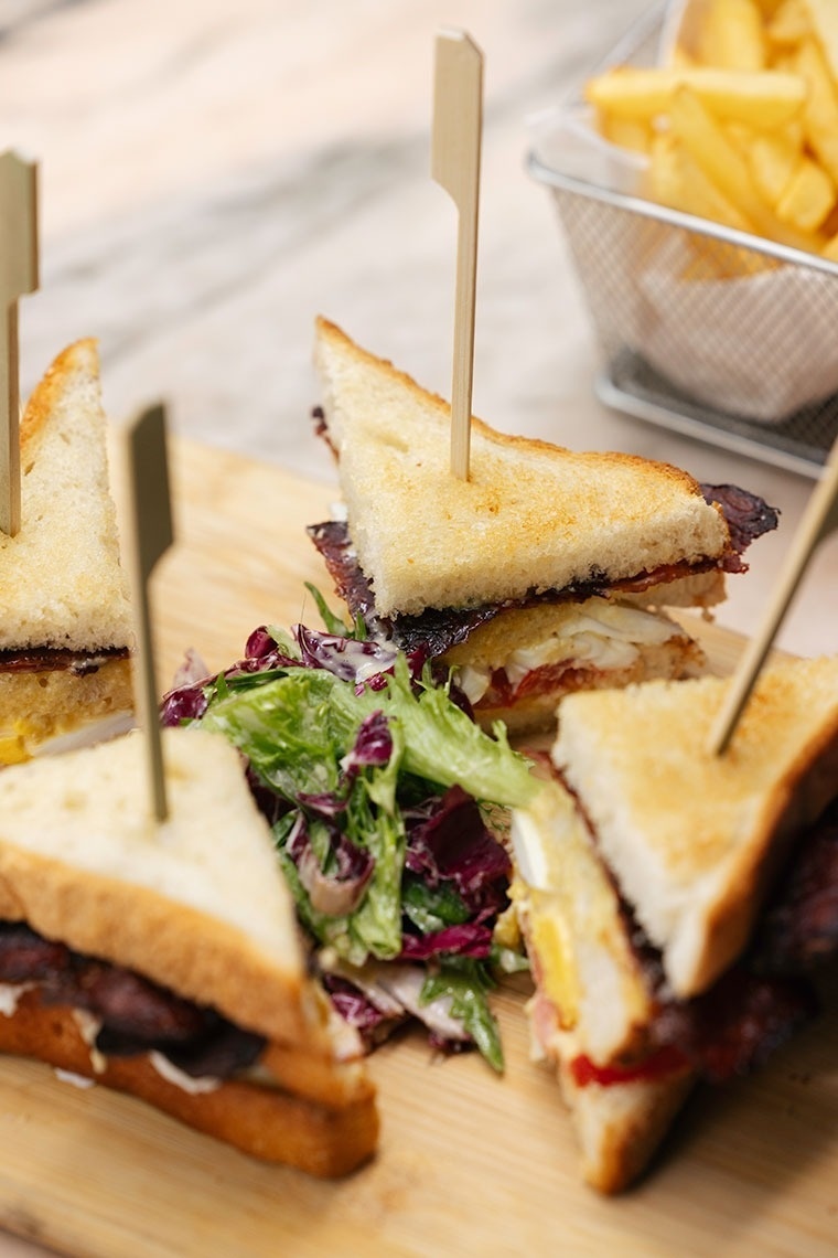 three sandwiches on a wooden cutting board with toothpicks in them