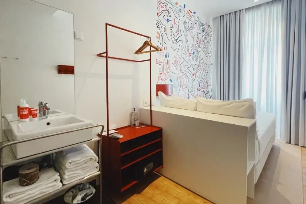 a bathroom in a hotel room with a sink and a shelf with towels on it