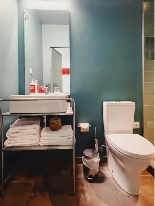 a bathroom with a toilet sink and a bottle of soap
