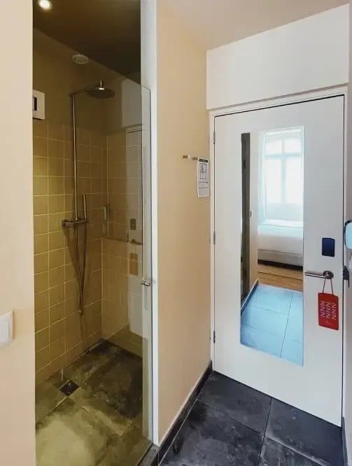 una puerta de vidrio que conduce a un baño con una ducha y un espejo .