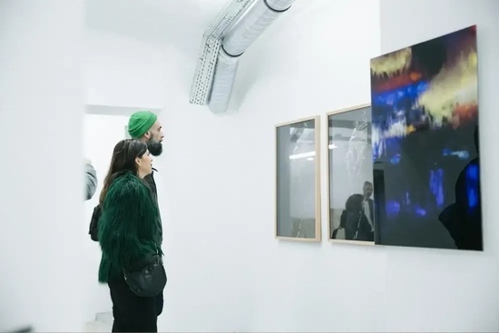 a man and a woman are looking at a painting on a wall