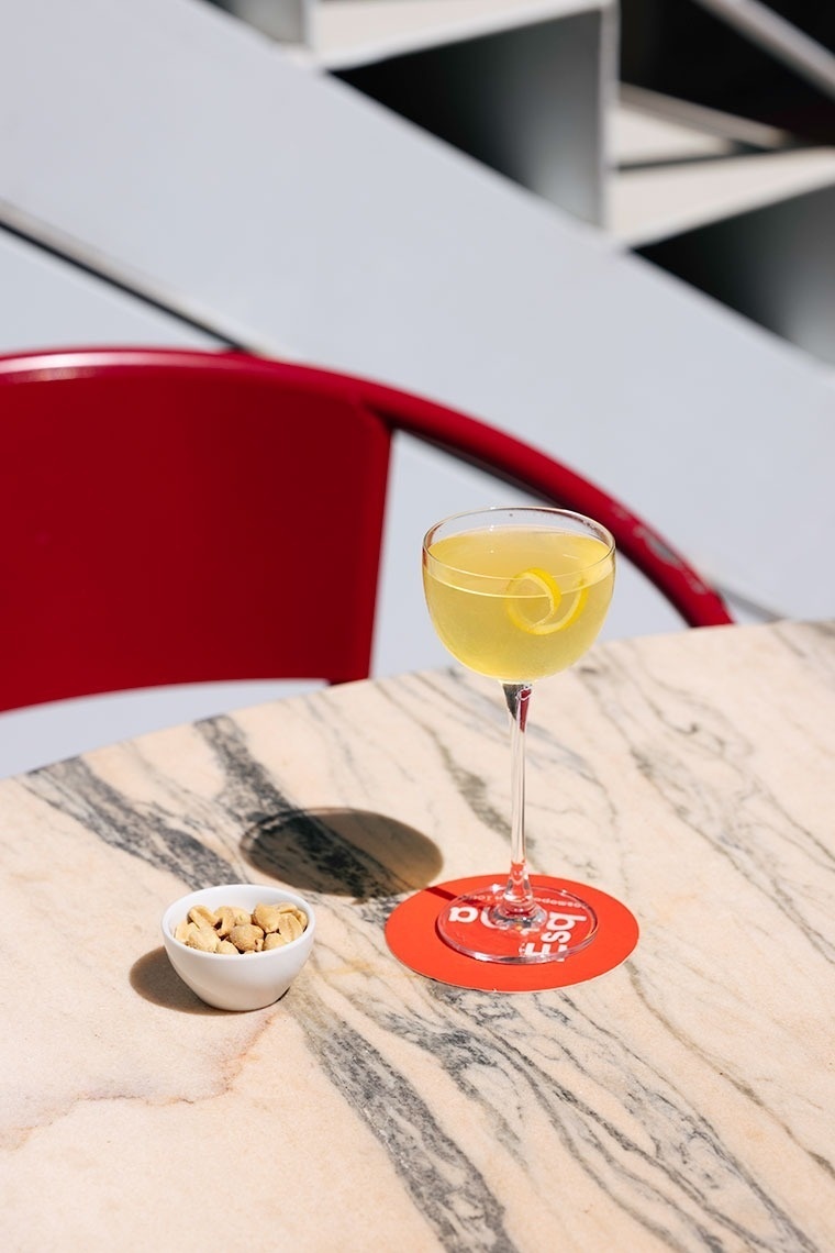 a marble table with a drink and a bowl of peanuts on it