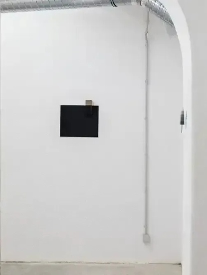 a white wall with a black square on it