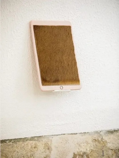 una tableta de piel marrón está colgada en una pared blanca .