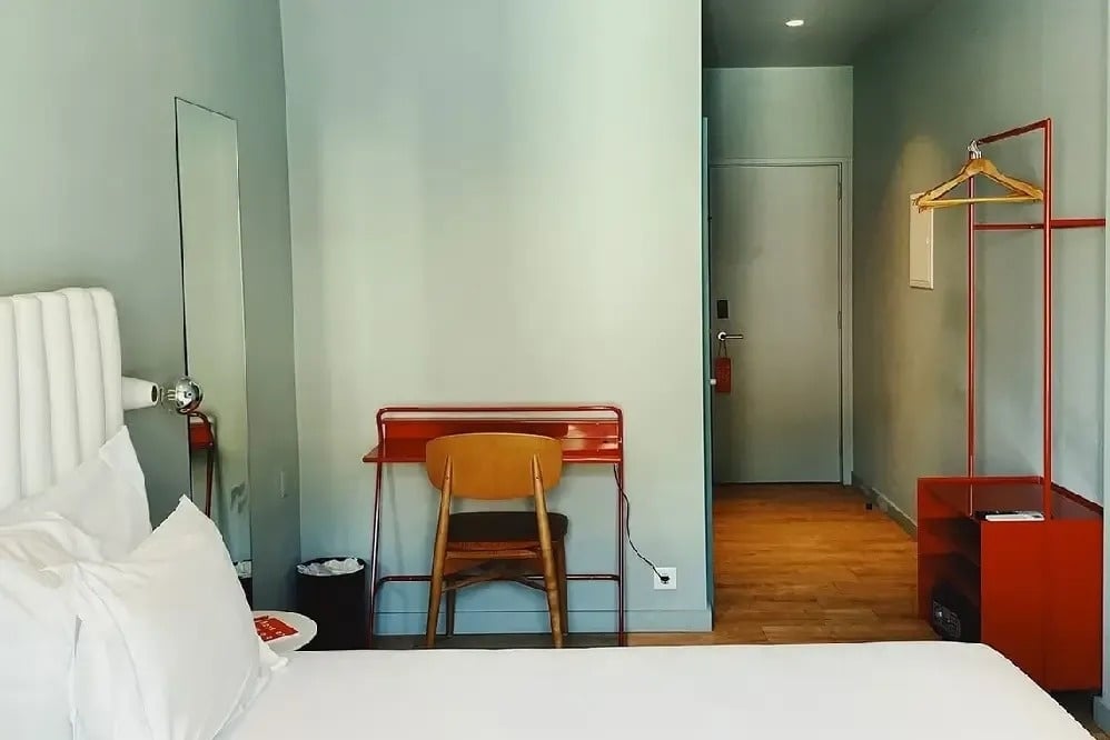 una habitación con una cama blanca y un escritorio rojo