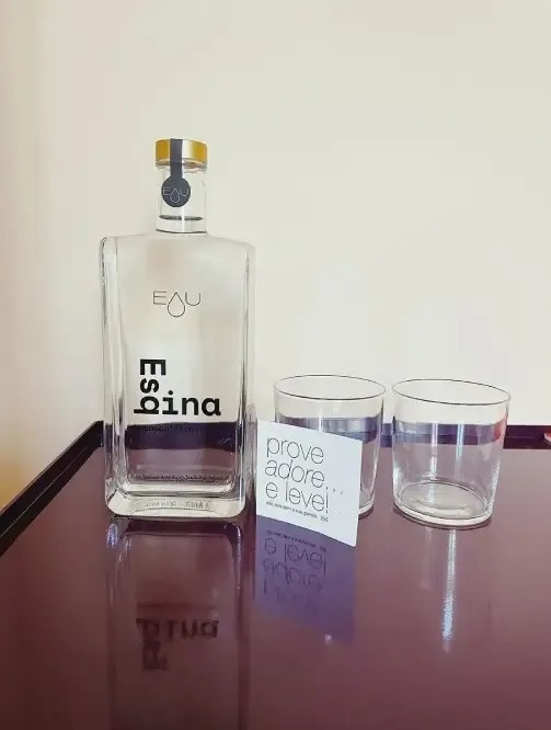 a bottle of eau espina sits on a table next to two glasses