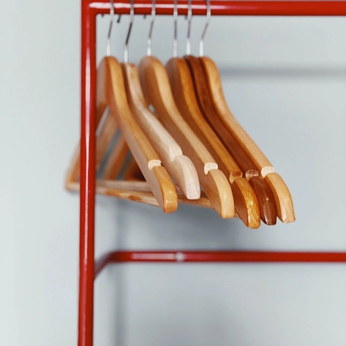 a row of wooden hangers hanging on a red rack