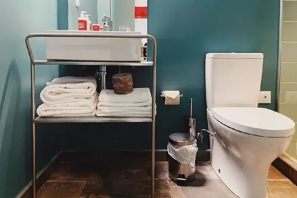 a bathroom with a toilet and a sink with a bottle of anti-bacterial soap