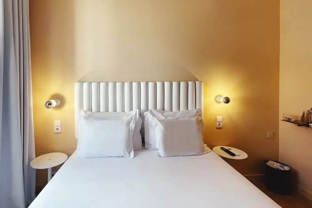 a bed with white sheets and pillows in a hotel room