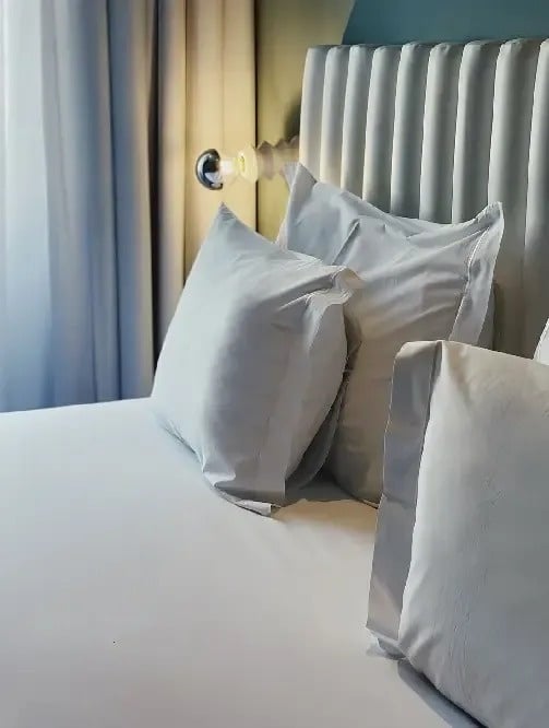 a bed with white sheets and pillows and a white headboard