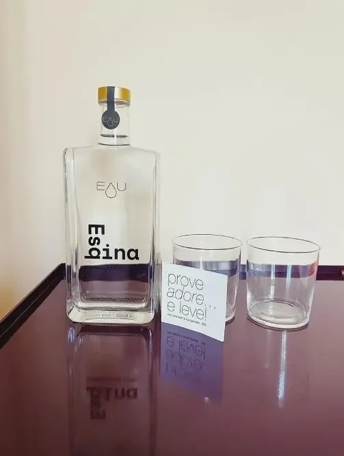 a bottle of eau espina sits on a table next to two glasses