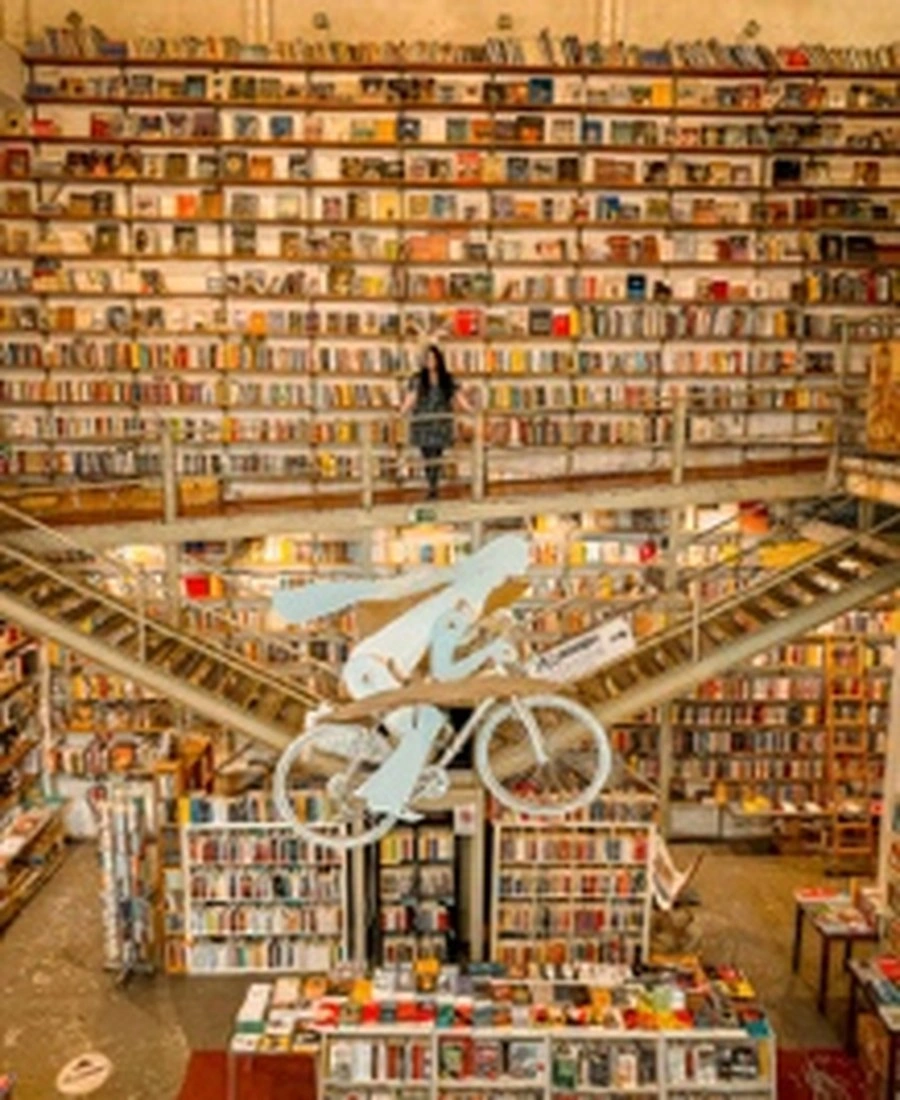Interior of the Ler Devagar bookstore with floor-to-ceiling bookshelves and a suspended bicycle.