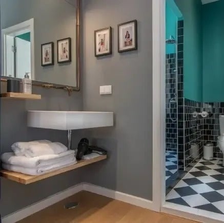 a bathroom with a sink , mirror , toilet and checkered floor .