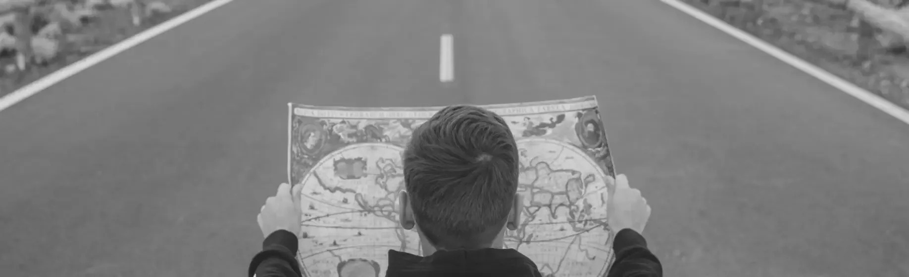 a black and white photo of a person looking at a map