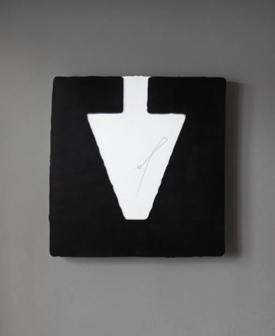 Black artwork with a white V-shape on a gray wall.