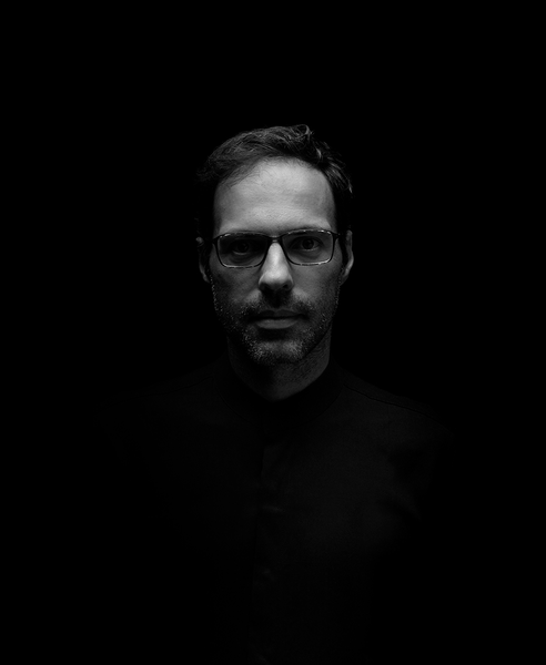 Man in dark room, possibly professional portrait for hotel service or staff. Esqina Urban Lodge
