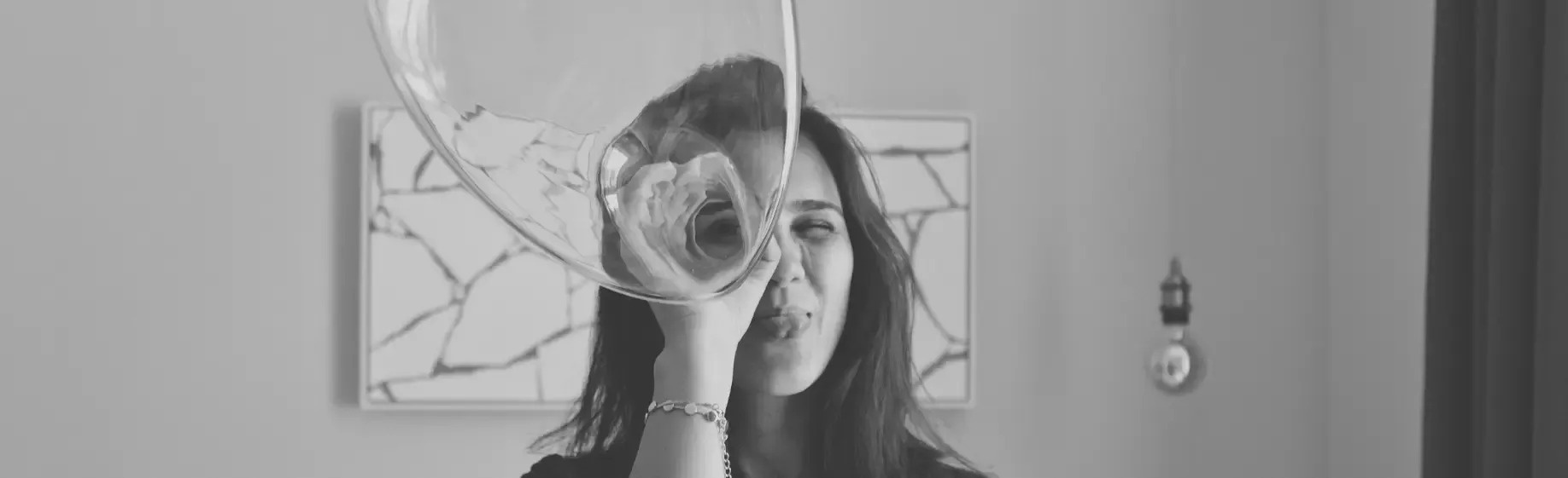 uma mulher está segurando um copo de vinho na frente de seu rosto .
