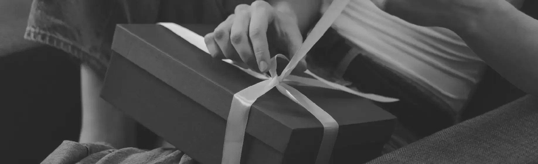 a woman is opening a gift box with a white ribbon